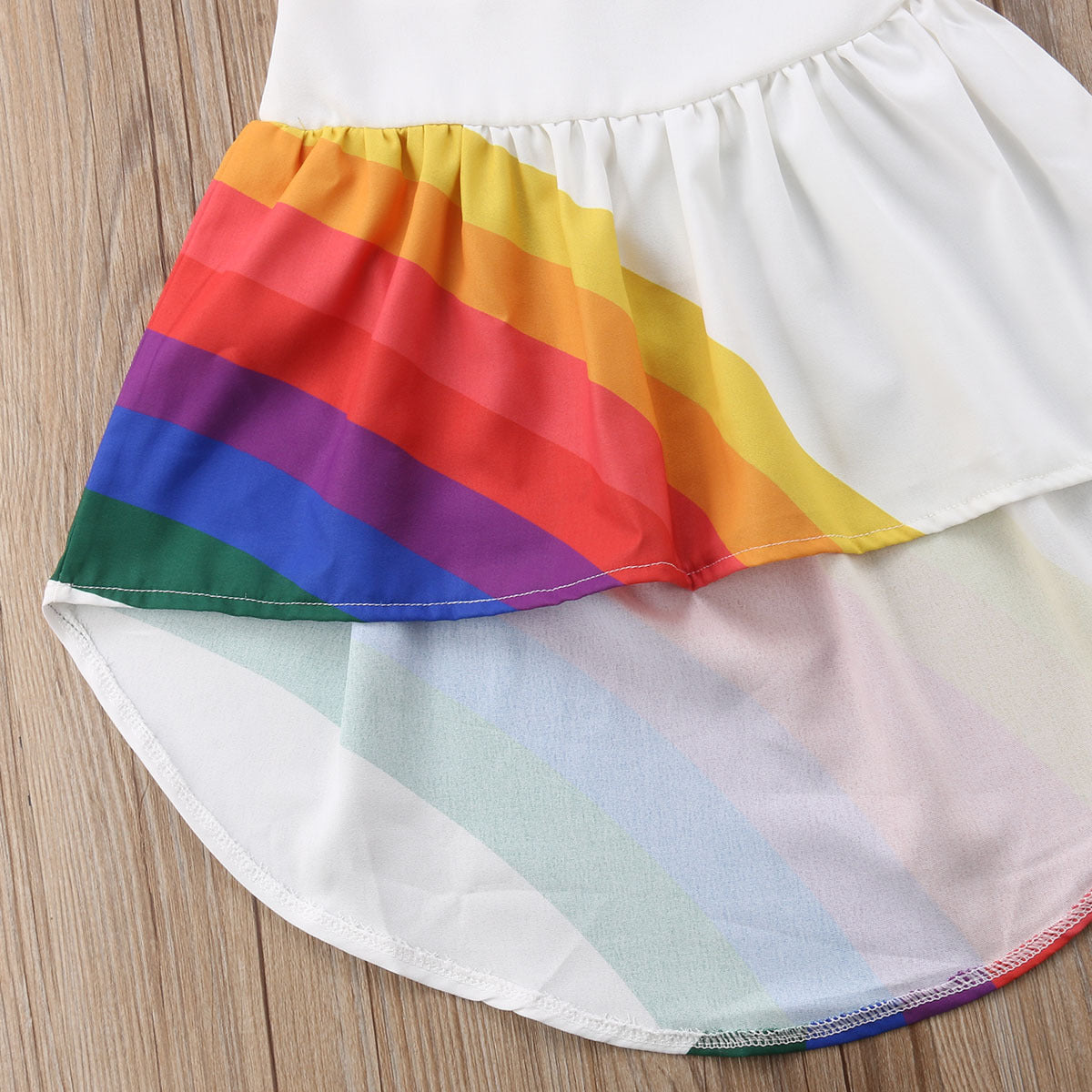 Rainbow stripe sleeveless cotton dress for girls, side view showing the longer back hem